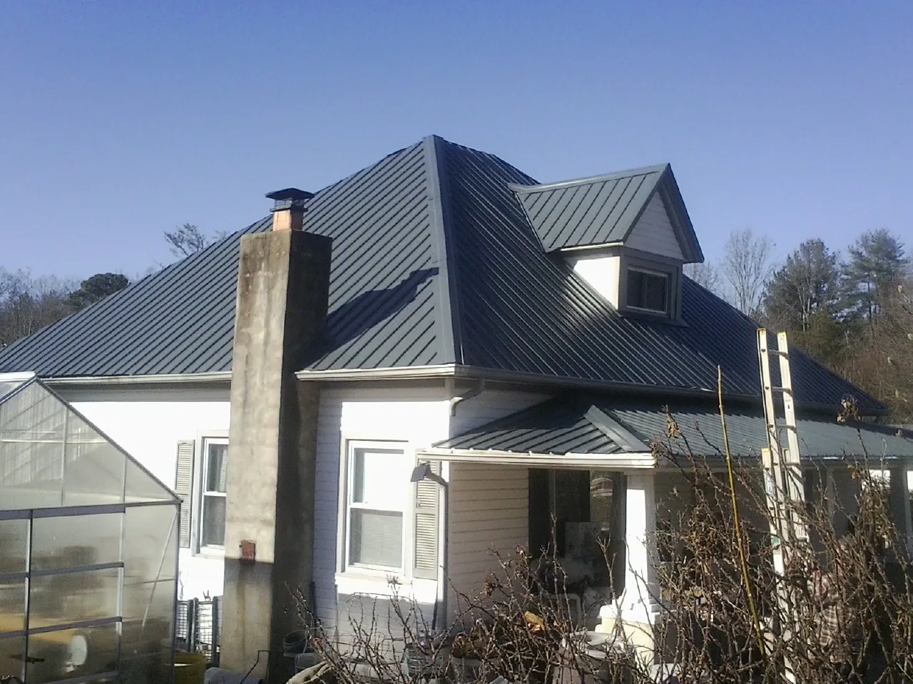 Dark blue standing seam metal roof on a white farmhouse with dormer — Slate & Tile Roof Repair by Roofing Brothers in New Tripoli