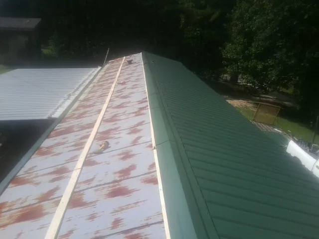 Old rusted panels beside newly installed green metal roofing — Wind Damage Roof Repair by Roofing Brothers in New Tripoli