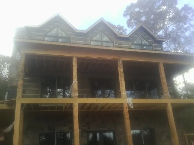 Dormers and porch framing on a large log home under construction — Roof Coating work by our crew in New Tripoli