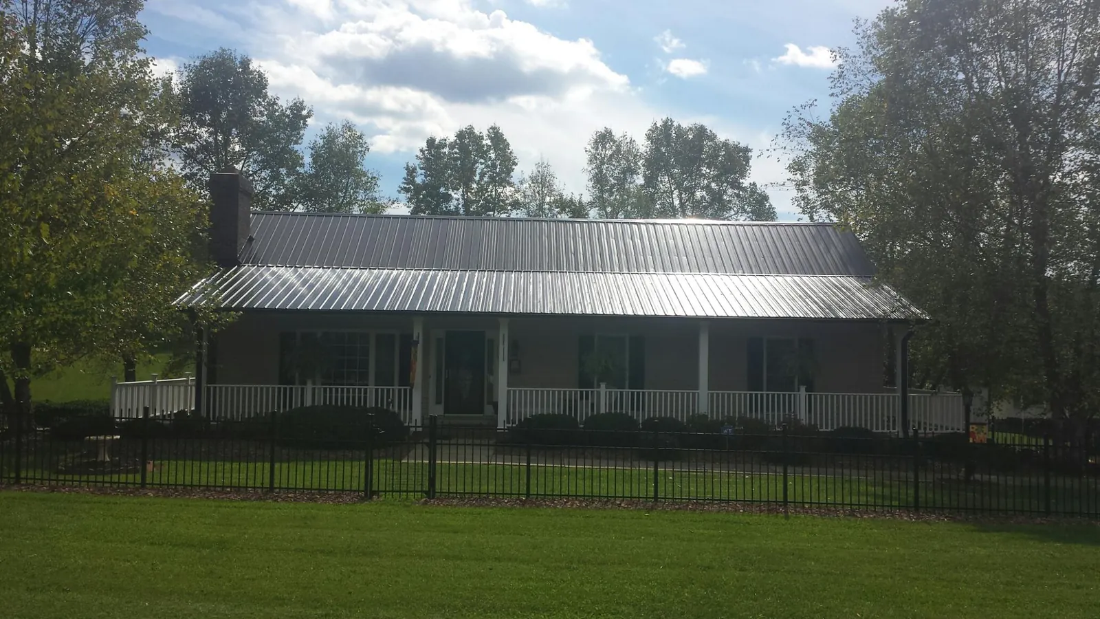 Gray metal roof on a brick ranch with a full width front porch — Gutter Guard Installation work by our crew in New Tripoli