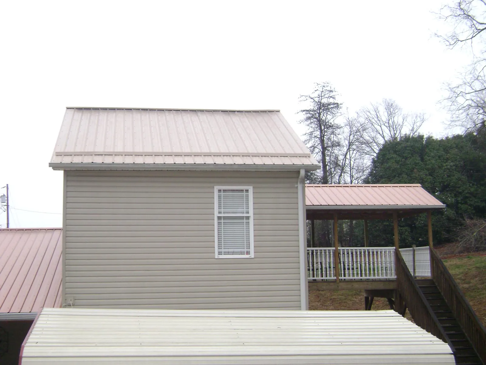 Tan metal roofs on a two story addition and attached porch, from a Roof Replacement job in New Tripoli