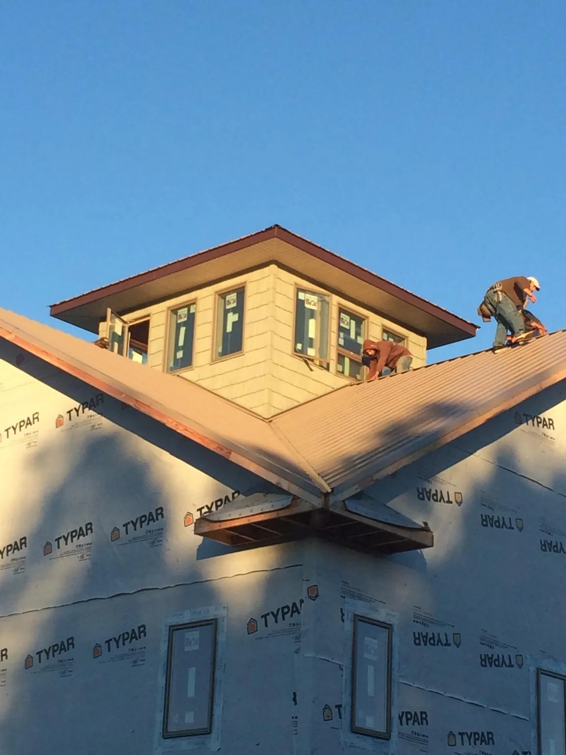 Roofers working around a rooftop cupola on a new metal roof at sunset — Roof Waterproofing in New Tripoli by Roofing Brothers